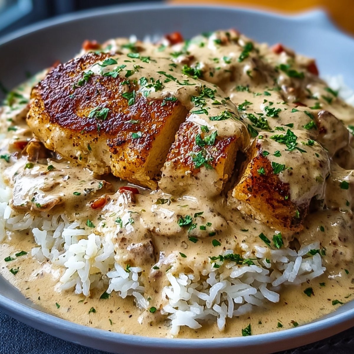 Plated creamy smothered chicken served over fluffy white rice, smothered in rich gravy and garnished with parsley.