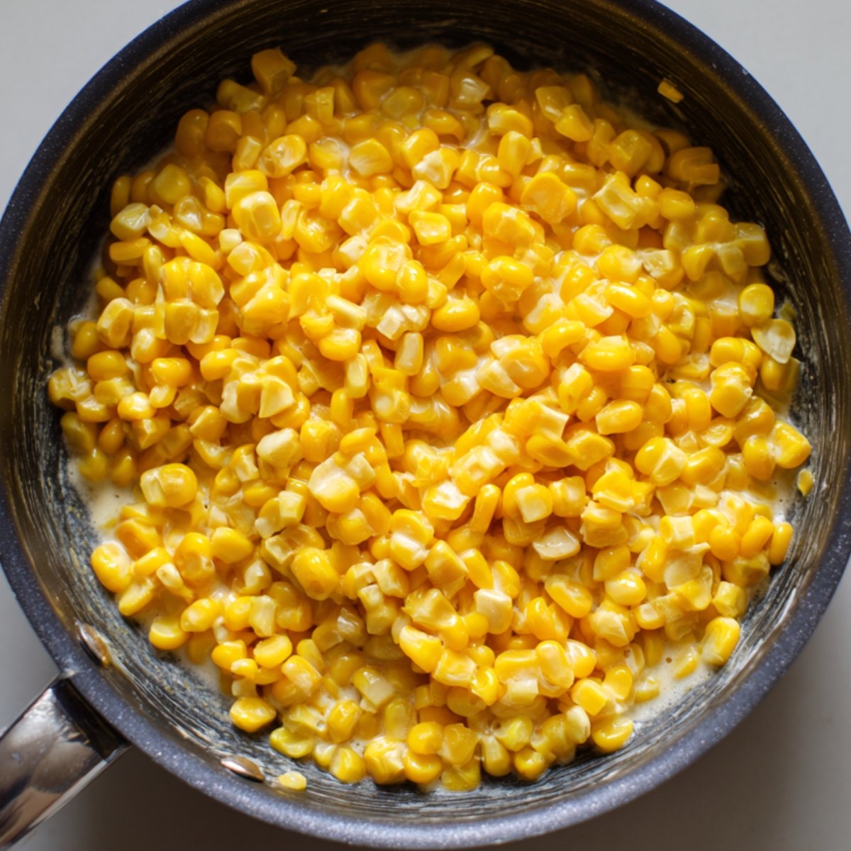 A pan filled with cooked corn coated lightly in cream.