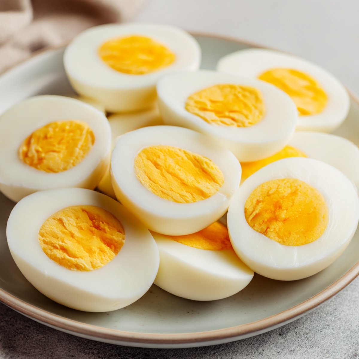Plate of halved hard-boiled eggs with bright yellow yolks, plain and ready to be made into deviled eggs.
