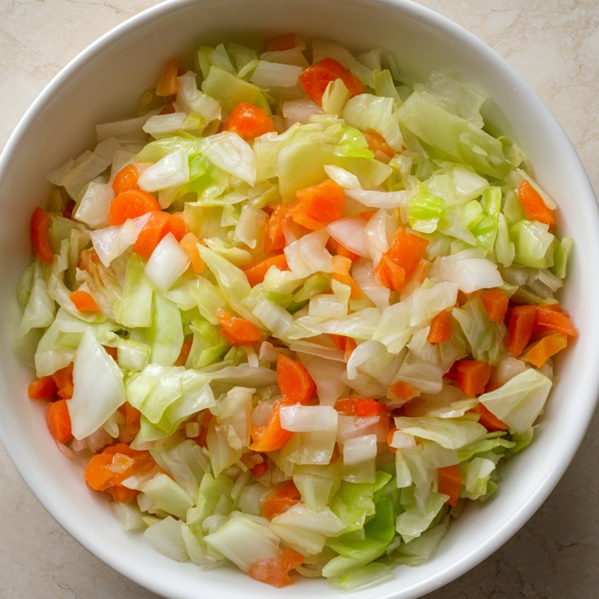 A bowl of freshly cooked chopped cabbage and carrots, lightly cooked until tender, ready to be added to soup.