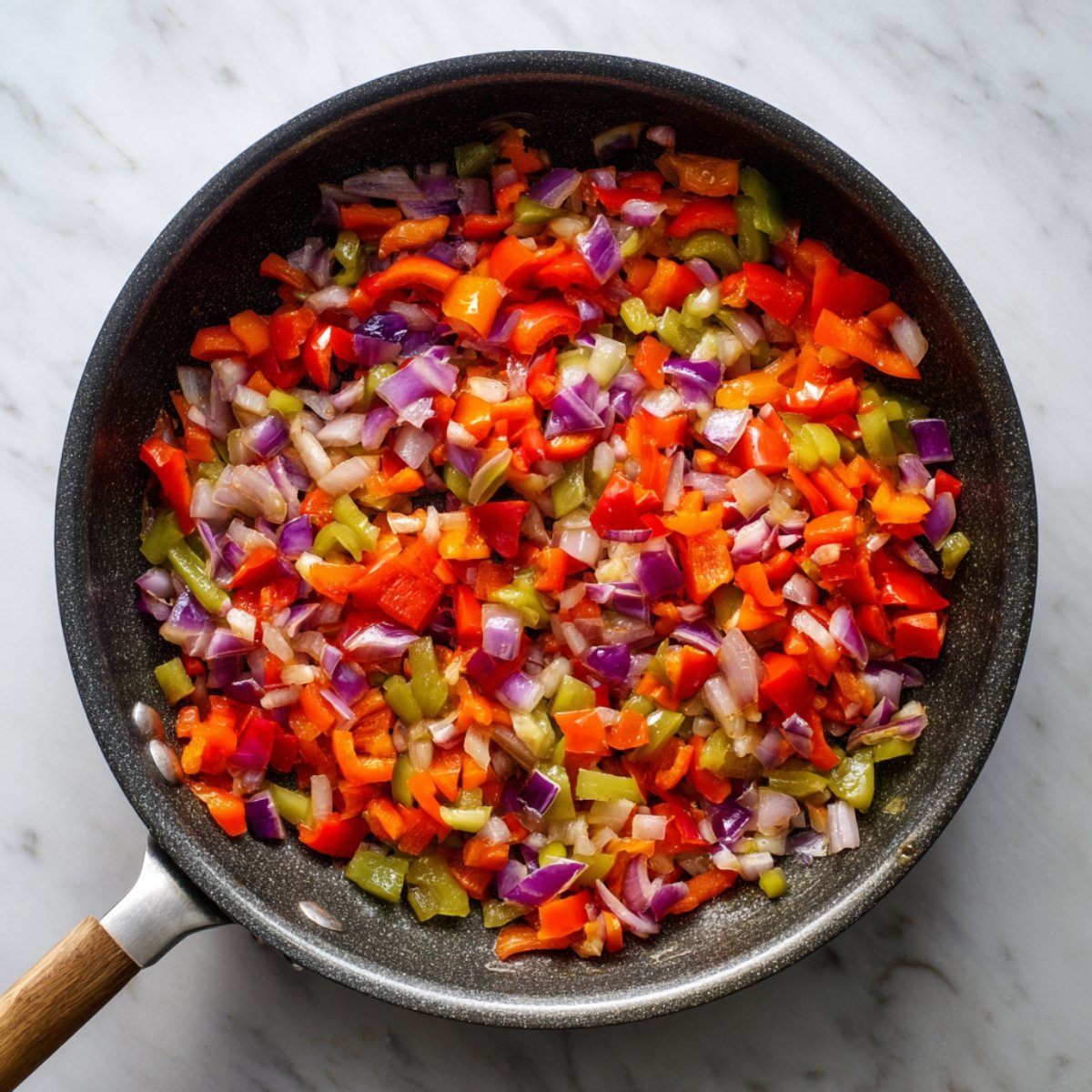 "Sautéed diced red onions, green, and red bell peppers in a skillet, glistening as they soften over heat."