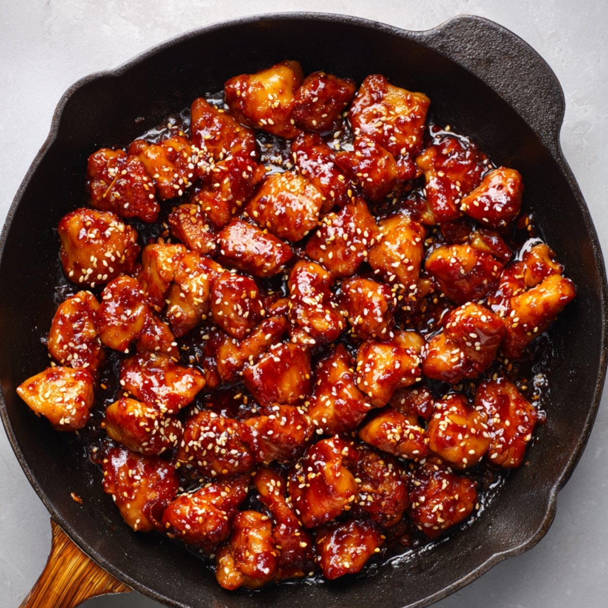 Skillet of Korean glazed chicken pieces topped with sesame seeds.