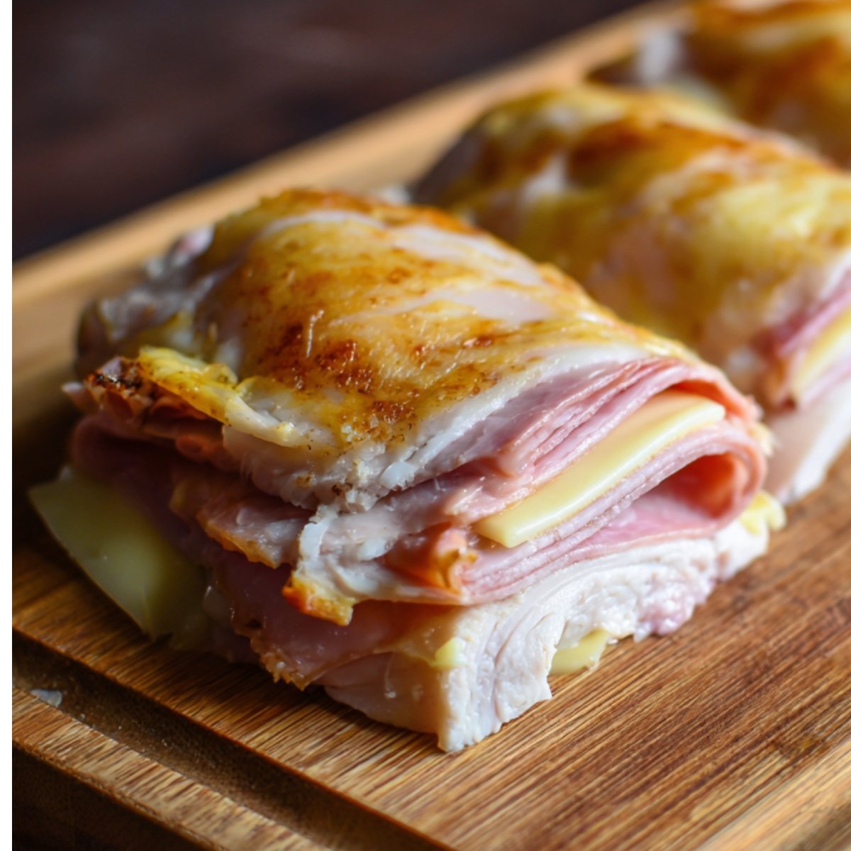 Close-up of layered chicken breast filled with ham and Swiss cheese, ready for rolling into cordon bleu.