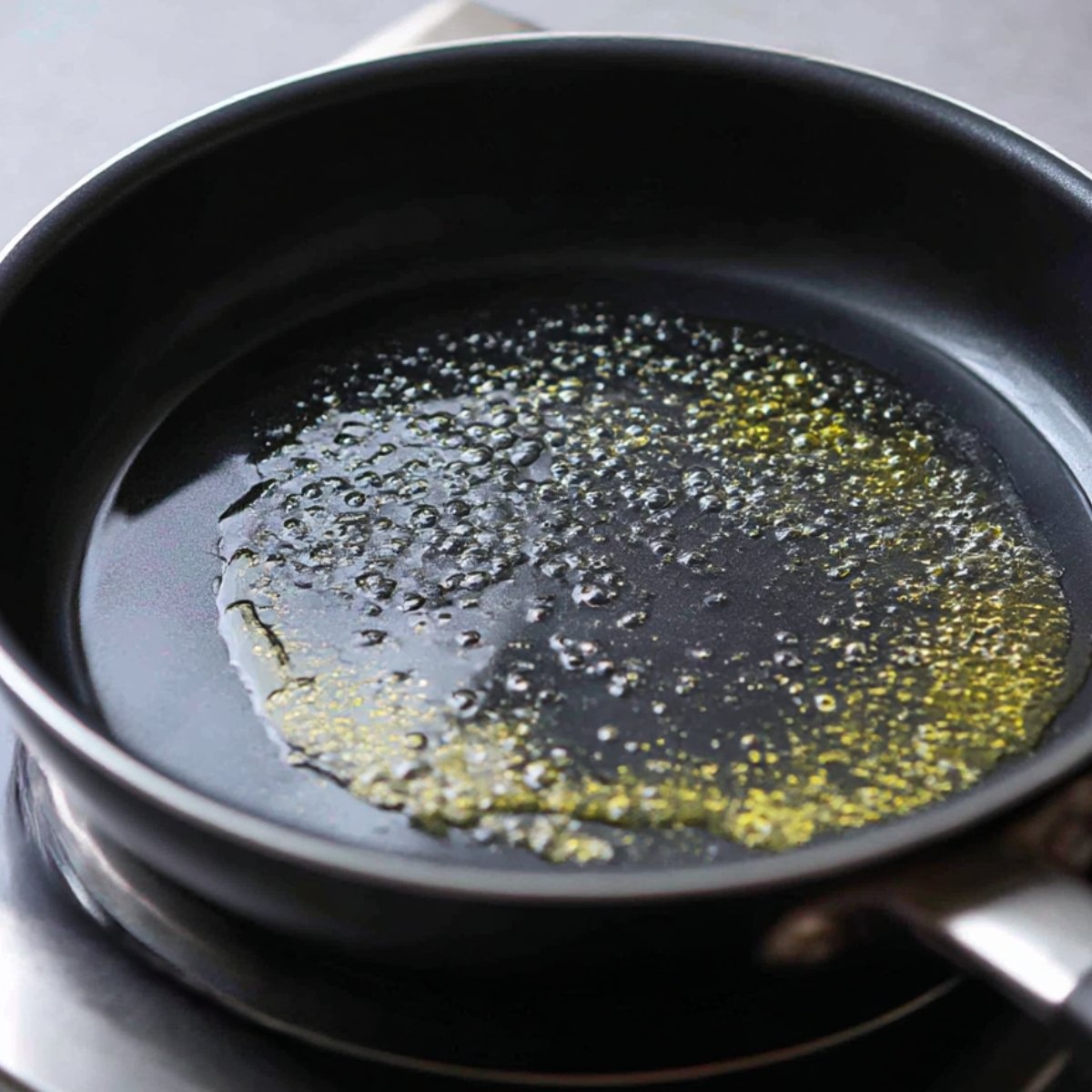 Nonstick pan with melted butter or oil bubbling, prepared for cooking tortillas.