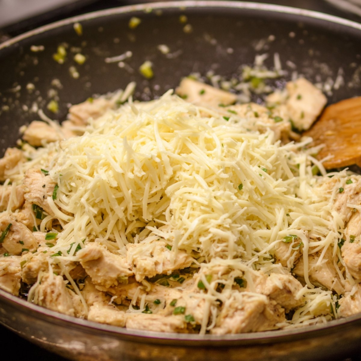 Rolled flour tortillas filled with chicken, placed in a baking dish, and topped with shredded cheese over a creamy white sauce.