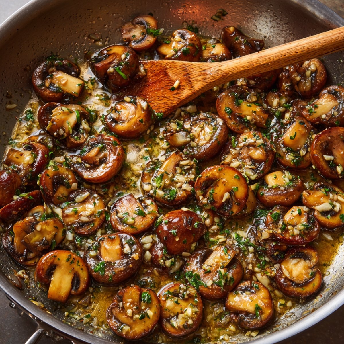 A skillet of sautéed mushrooms with garlic and parsley, cooking in a flavorful butter and herb mixture.