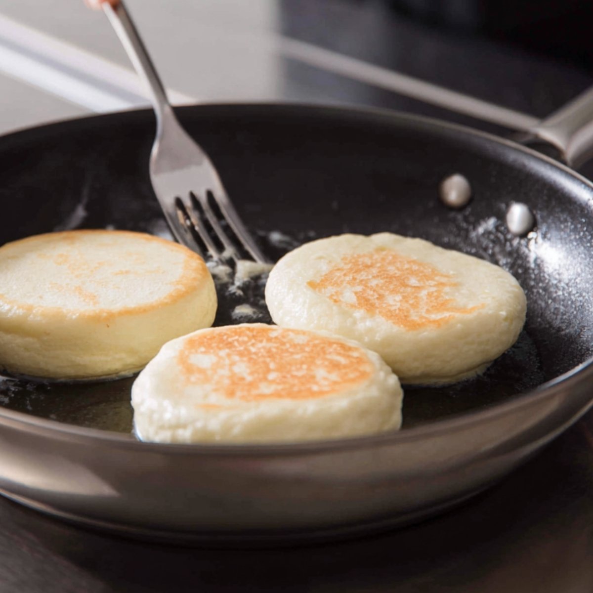 "Flipping fluffy Japanese pancakes in a frying pan with a fork."