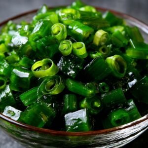 Bowl of chopped fresh green onions glistening under light.
