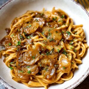 A serving of French onion pasta with caramelized onions, garnished with fresh parsley.
