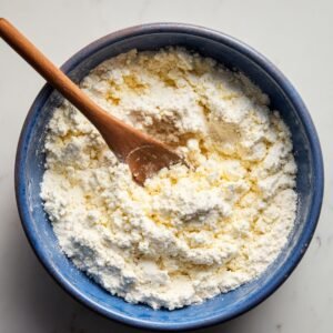 "Blue ceramic bowl filled with fresh cottage cheese and a wooden spoon."