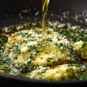 Close-up of garlic butter with herbs, parmesan, and oil sizzling together in a pan to make the garlic parmesan glaze.