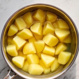 Chunks of potatoes in a pot filled with water, ready for boiling.