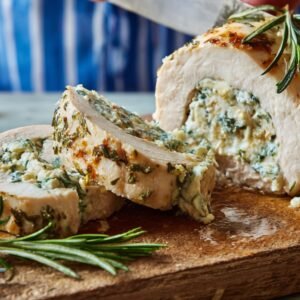 Sliced chicken Kiev on a wooden board, filled with a herb and garlic butter stuffing, garnished with fresh rosemary.