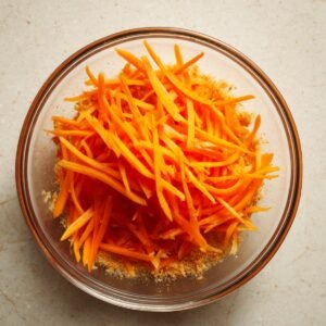 Bowl of thinly sliced carrots marinating in quick pickle seasoning.