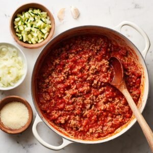 "Layered zucchini lasagna slice served on a white plate, showing zucchini strips, marinara sauce, and melted cheese."