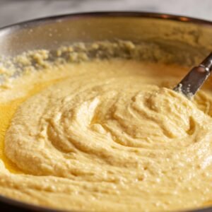 Thick, creamy biscuit batter being stirred in a mixing bowl with a spatula.