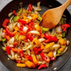 A close-up of ground beef being sautéed in a pan, showing the texture and seasonings being added for the Sloppy Joe mix.