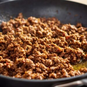 A detailed step-by-step preparation for Sloppy Joe, including cooked beef and seasonings in a frying pan, ready to be added to buns for the final sandwich.